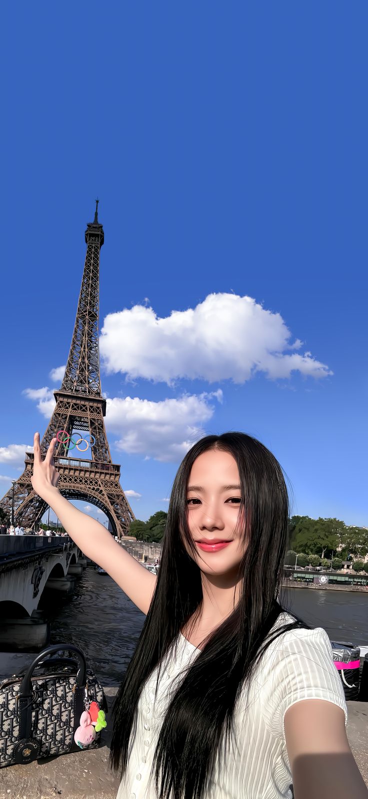 a woman standing in front of the eiffel tower with her hand up to the sky