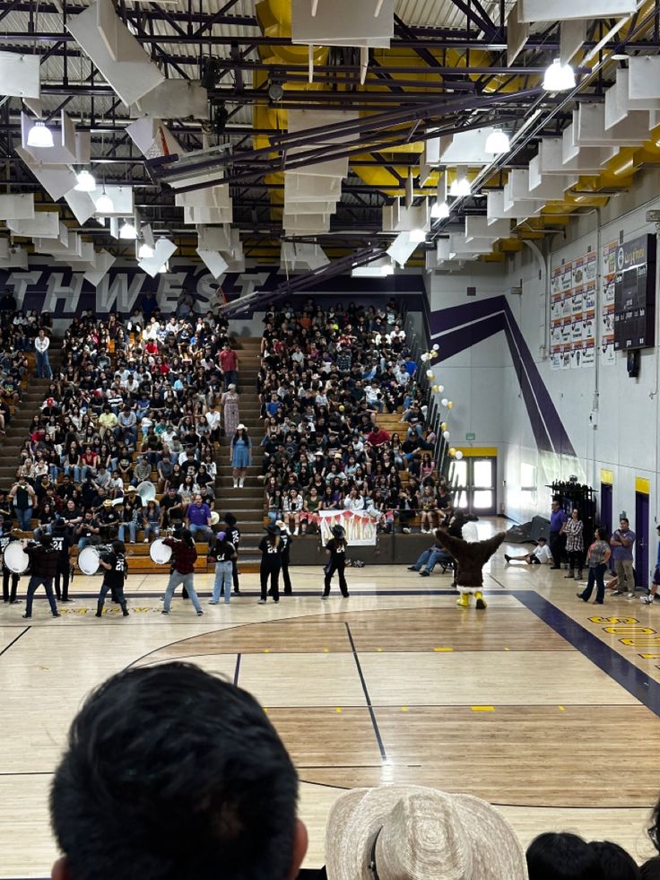 a large group of people standing on top of a basketball court in front of an audience