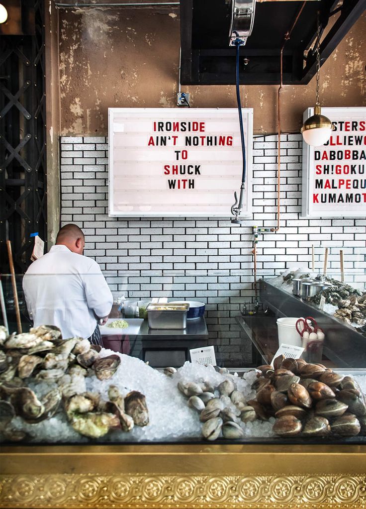 a man standing in front of a counter filled with oysters