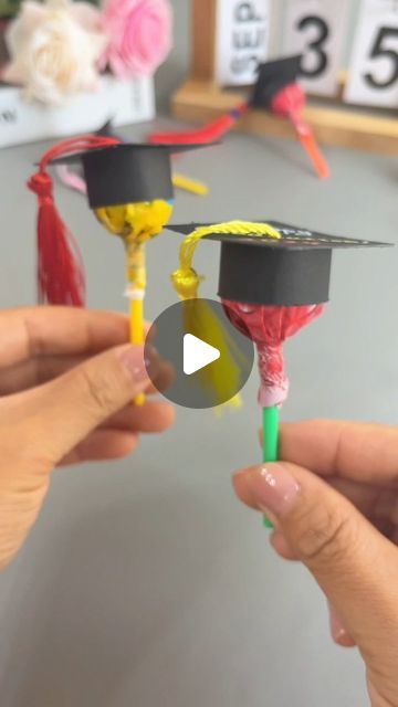 two people are holding graduation caps and tassels