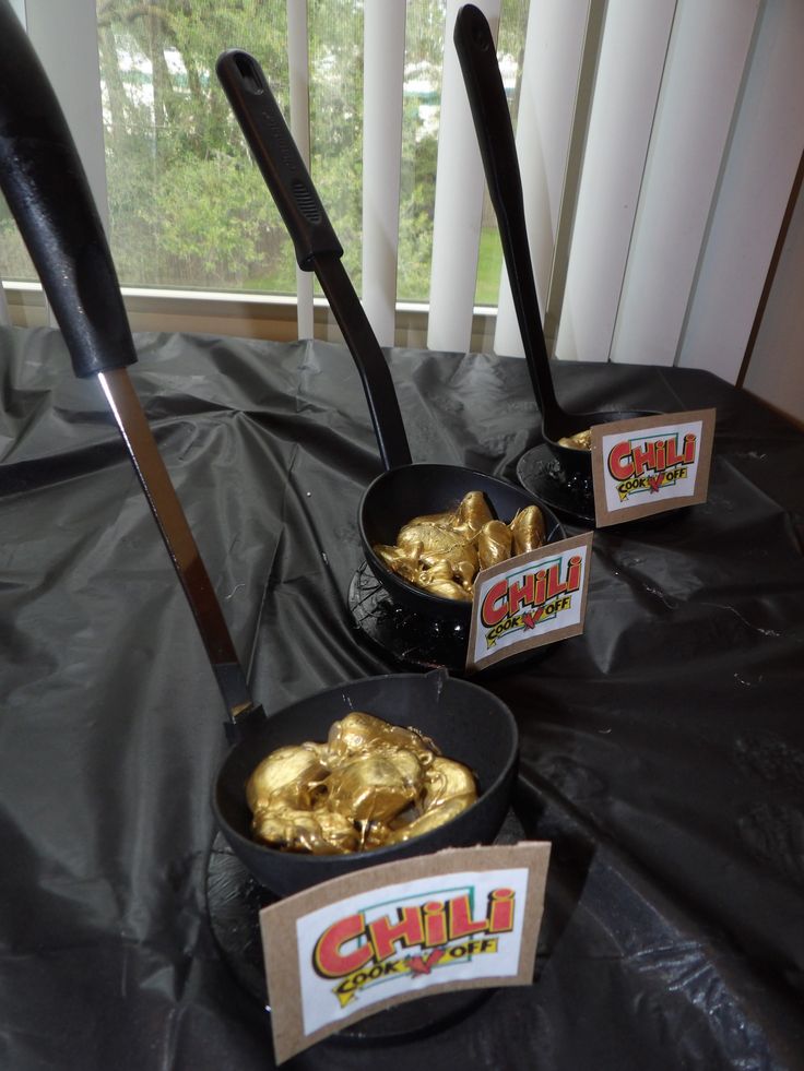 three black pans filled with gold foil on top of a table next to a window