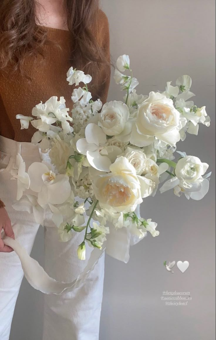 a woman holding a bouquet of white flowers