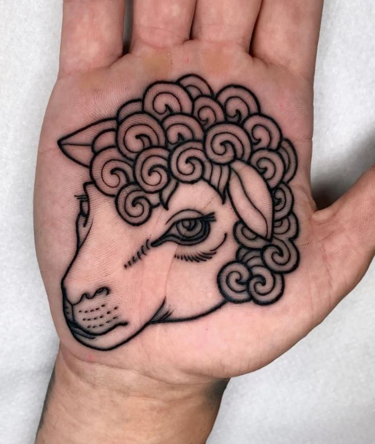 a hand with a black and white sheep tattoo on it