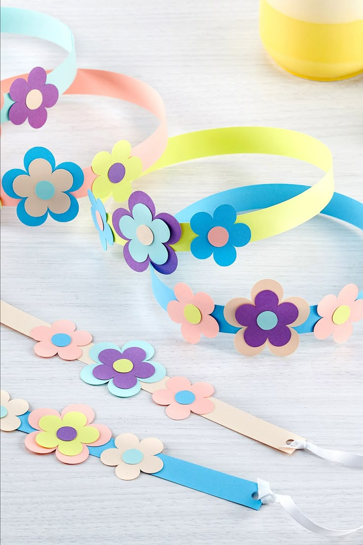 colorful paper flowers and ribbons on a white table next to tape, scissors and other crafting supplies