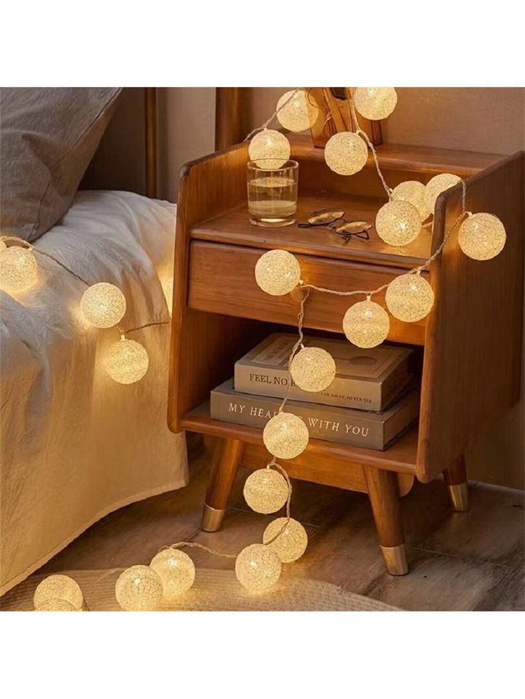 a night stand with some lights on top of it and books in front of it