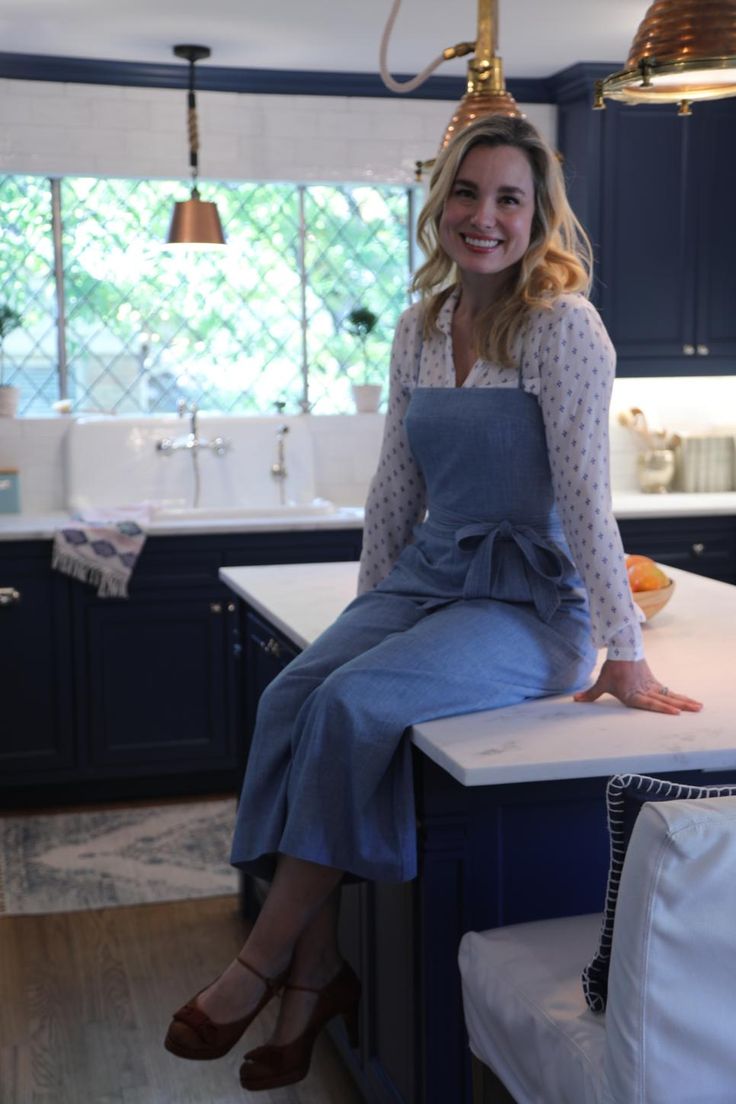 a woman sitting on top of a kitchen counter