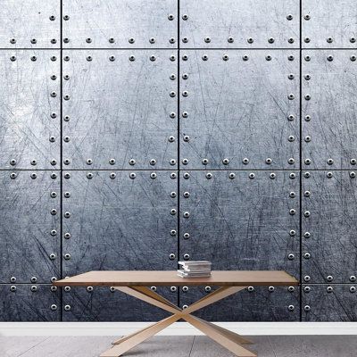 a table sitting in front of a metal wall with rivets on the side