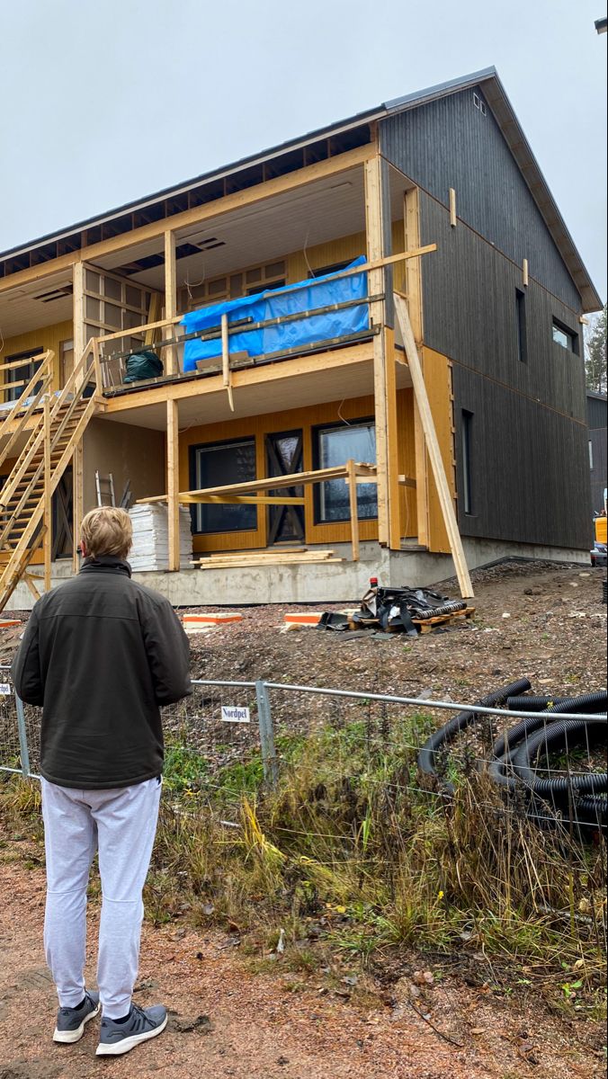 a man standing in front of a house under construction