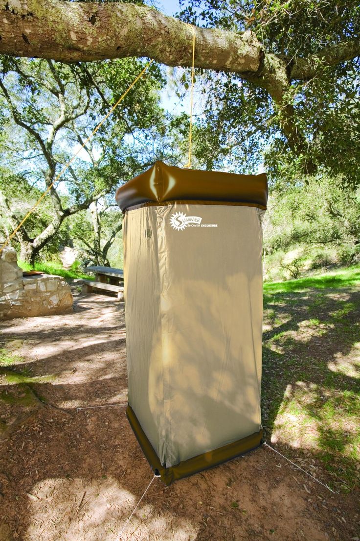 an outhouse in the shade under a large tree with a canopy on it's side