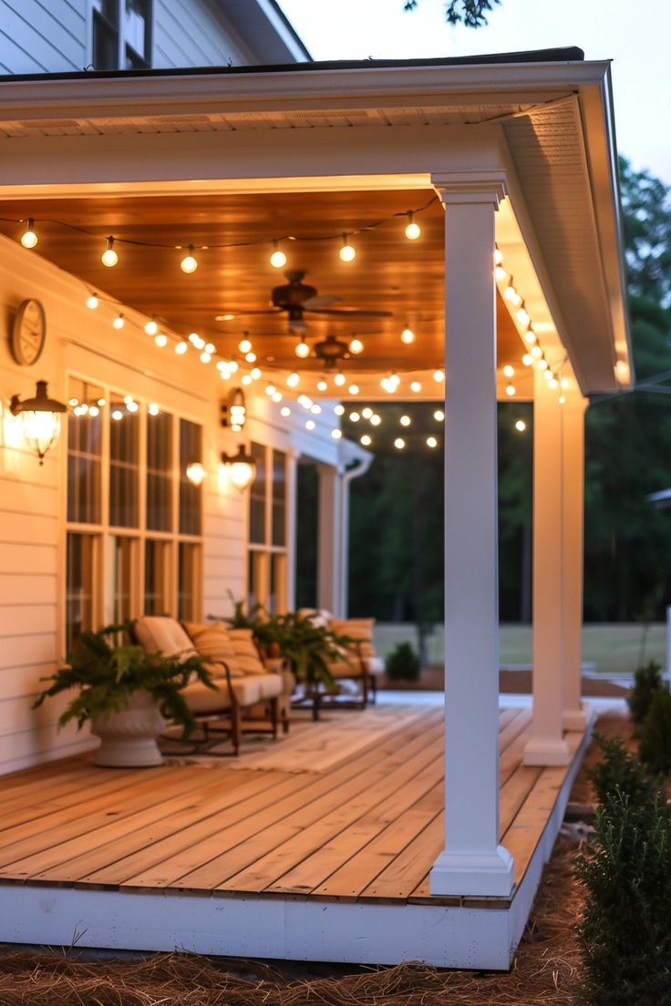 an outdoor deck with lights and chairs on it