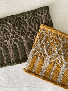 two knitted clutches sitting on top of each other next to each other, one with an intricate design