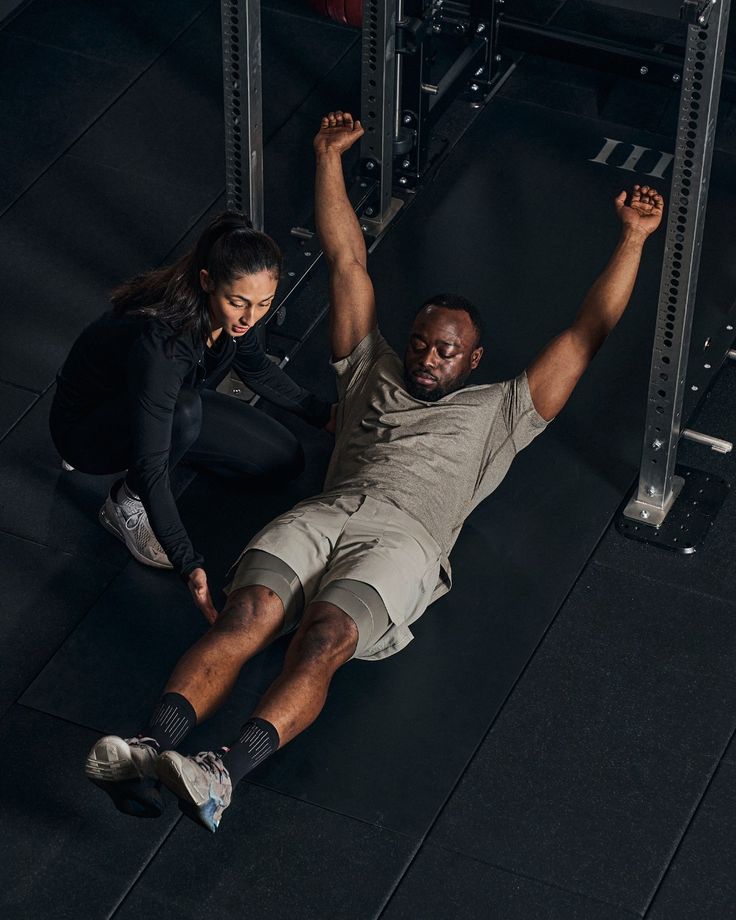 a man and woman doing push ups in a gym