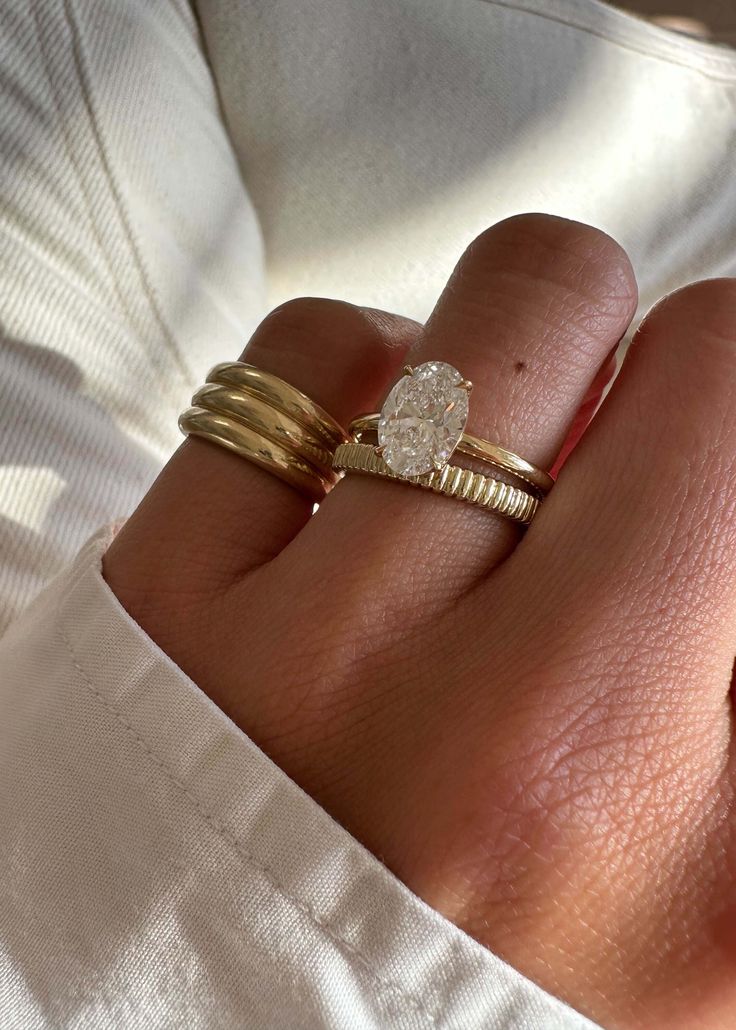 a woman's hand with two gold rings and a diamond ring on her finger