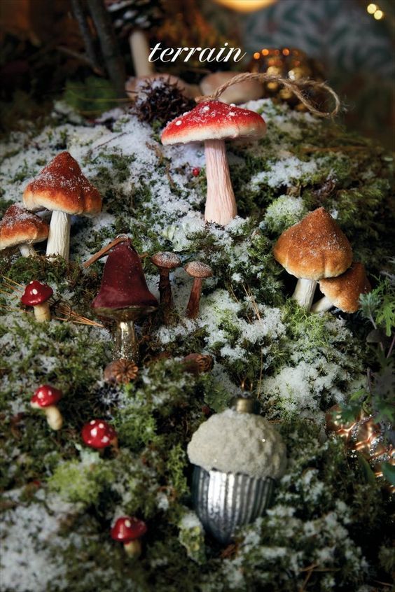 small mushrooms are growing on the mossy ground in front of christmas lights and garlands