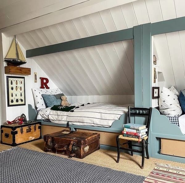 an attic bedroom with two beds and suitcases on the floor