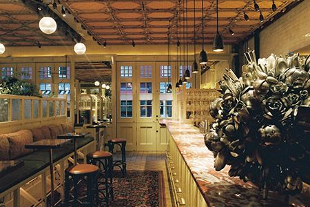 a restaurant with tables, chairs and lights hanging from the ceiling