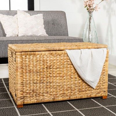 a living room with a gray couch and wicker storage box on the floor next to it