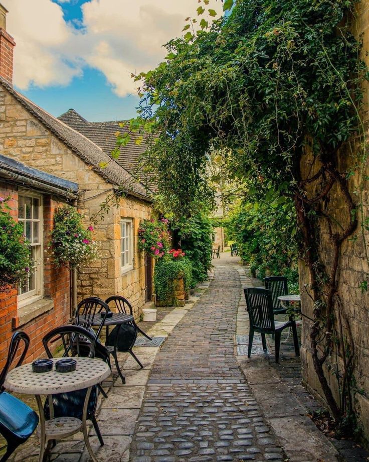 an alley way with tables and chairs lined up along the side of each other on cobblestone streets