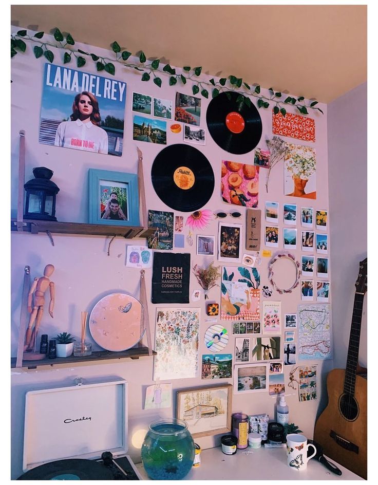 a wall with many pictures and records hanging on it's side, including a guitar