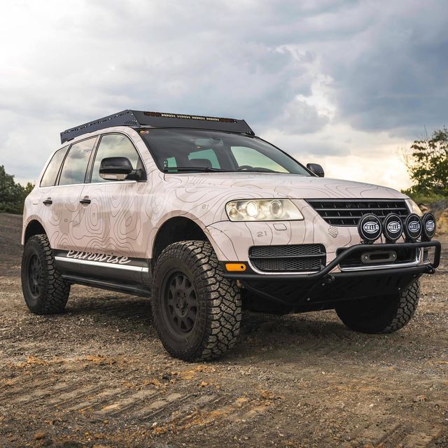 a white suv parked on top of a dirt field