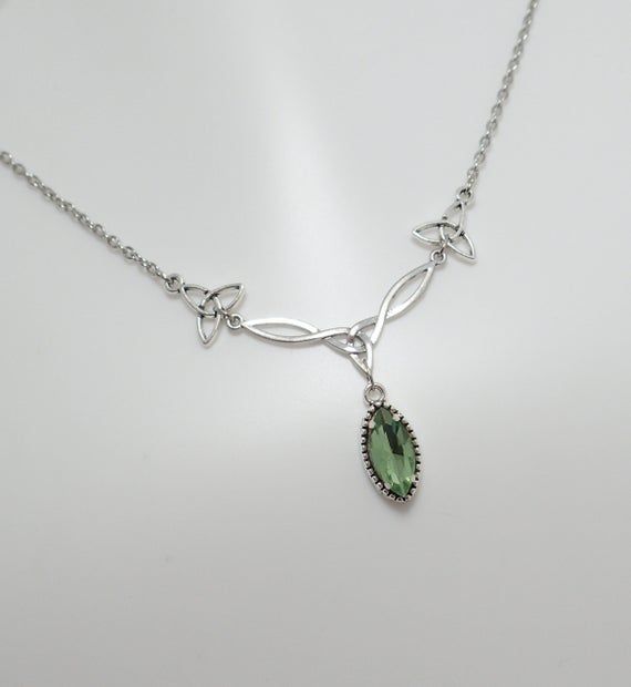 This is a new handmade necklace. It is made with antiqued silver plated Celtic knots, accented with a high quality LIGHT PERIDOT GREEN glass jewel that sparkles like crystal. Decorated portion is 2 1/2" wide and 1 1/4" tall in the center. Necklace is adjustable 15-18" with a lobster clasp and chain extender. If you would like a different length, please send us a message.Matching earrings and headpiece are listed in our store in a variety of stone colors. If you don't see items with a color you w Elven Wedding Jewelry, Elven Jewelry Earrings, Silver Green Necklace, Celtic Inspired Outfits, Peridot Necklace Silver, Silver And Green Necklace, Silver And Green Jewelry, Green Necklace Aesthetic, Green Wedding Necklace