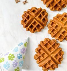 three waffles on a table with a party hat and dog paw print napkin