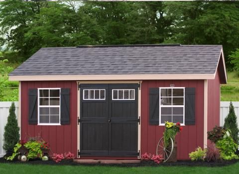 a red shed with black shutters and windows