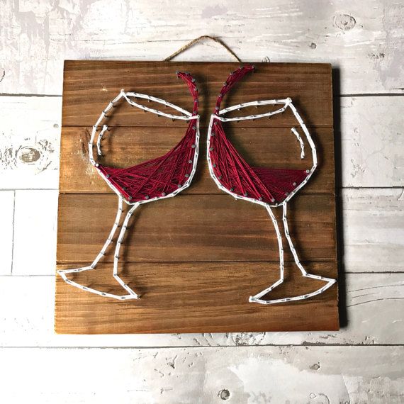 two wine glasses made out of yarn sitting on top of a wooden board with string