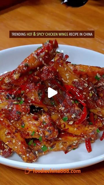 a white plate topped with fried chicken wings covered in sauce and seasoning on top of a wooden table