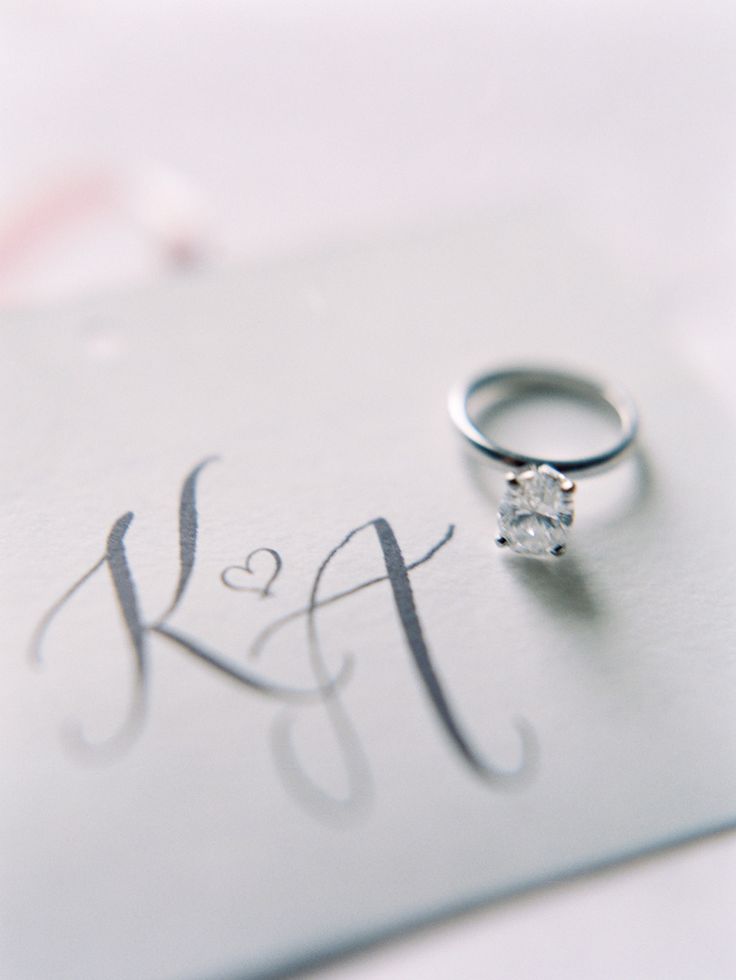 a wedding ring sitting on top of a piece of paper with the word k & f written in cursive writing