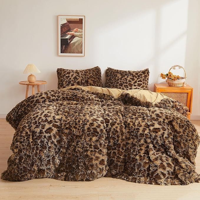 a leopard print comforter set on a bed in a room with white walls and wooden flooring