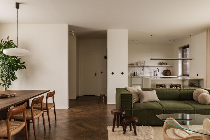 a living room filled with furniture next to a kitchen and dining room table on top of a hard wood floor