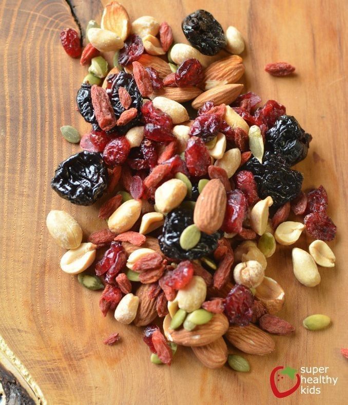 mixed nuts and dried cranberries on a wooden cutting board