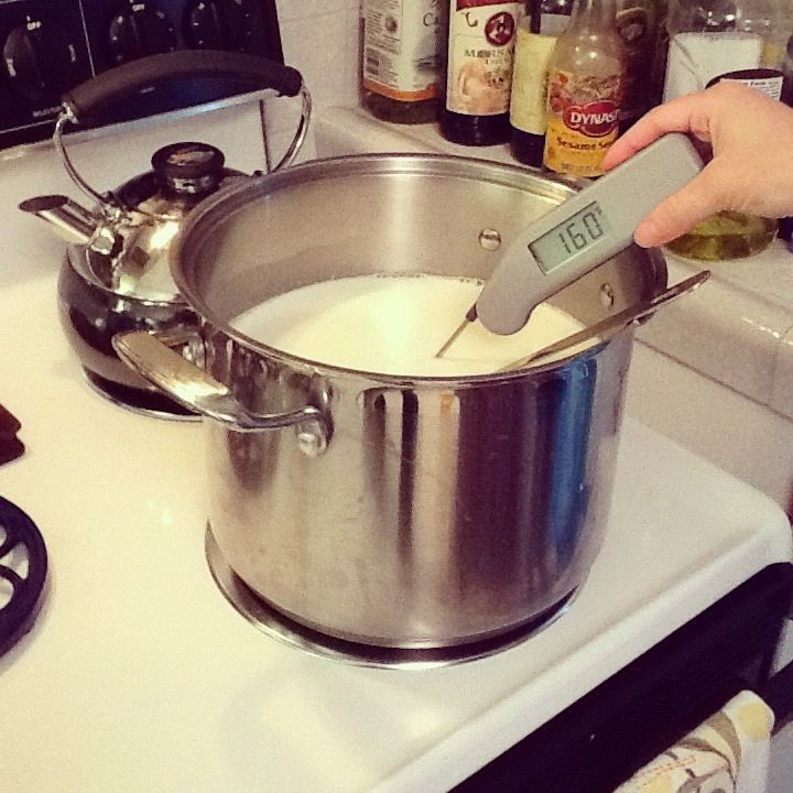 a person using a digital thermometer to measure something in a pot on top of a stove