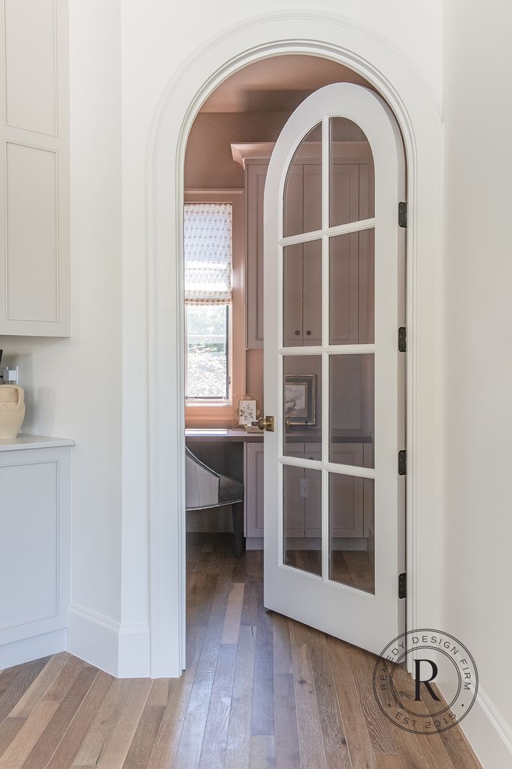 an open door leading to a kitchen with wood floors and white walls, along with hardwood flooring