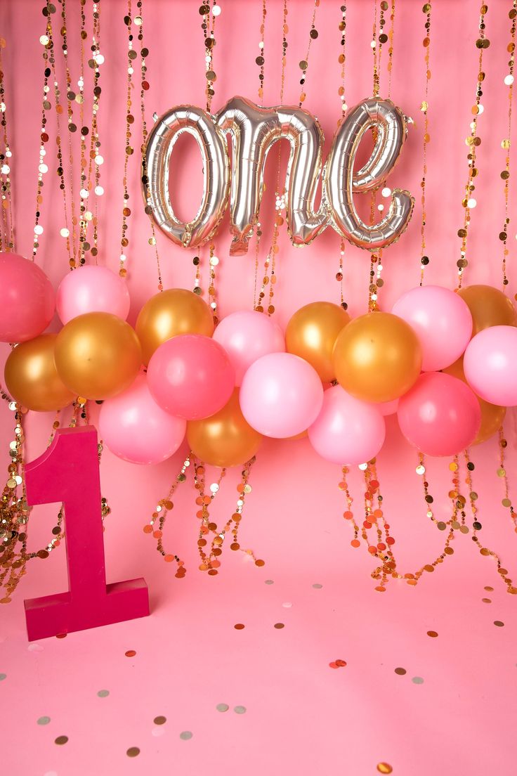 a pink and gold 1st birthday party with balloons, confetti and streamers