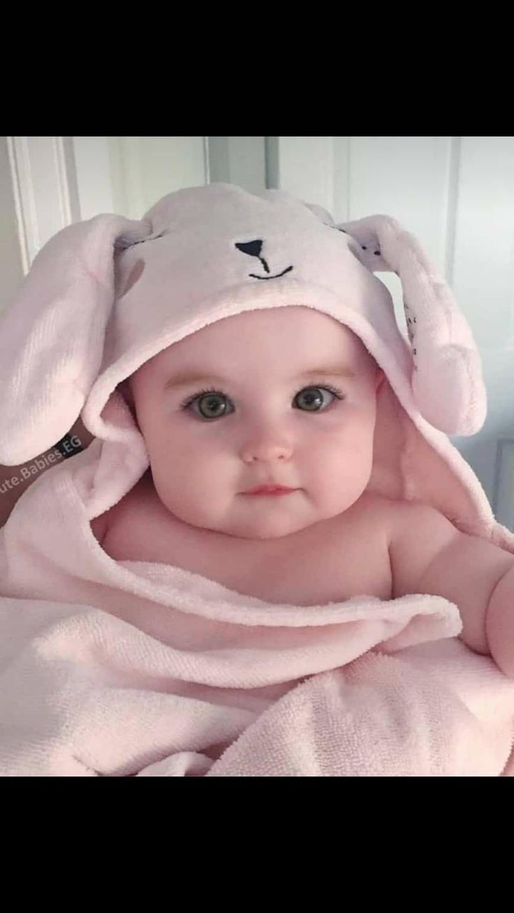 a baby wrapped in a pink bunny towel with ears on it's head and eyes wide open