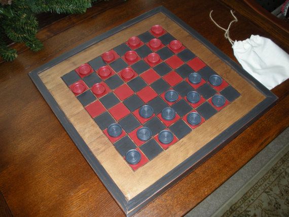 a wooden chess board with red and black pieces on it, next to a christmas tree