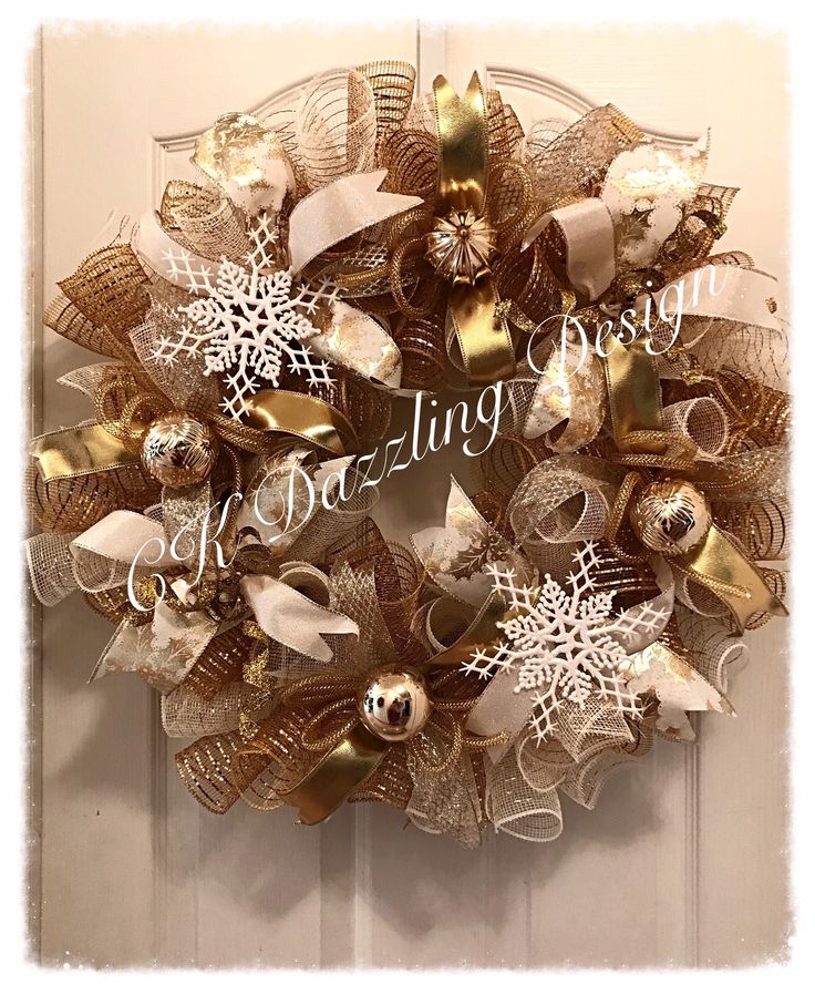 a gold and white christmas wreath hanging on the front door with snowflakes