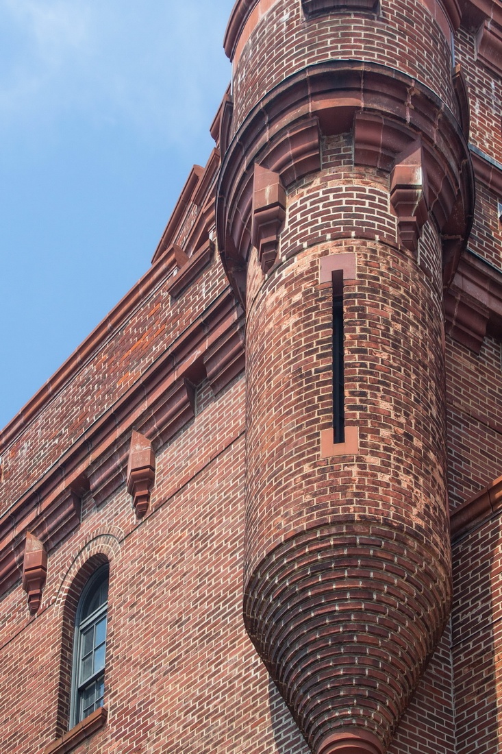 a large brick building with a clock on the front and side of it's face