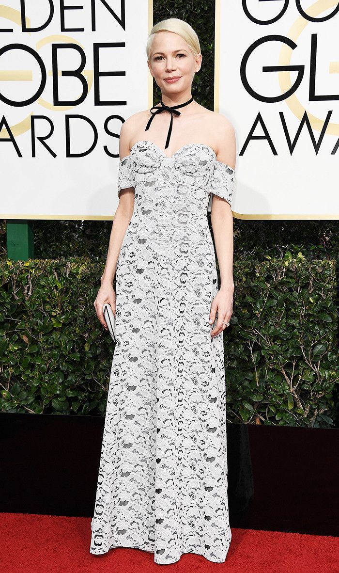 a woman in a white and black dress on the red carpet at an awards event