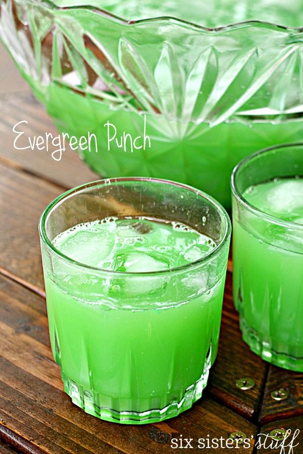 two glasses filled with green punch sitting on top of a wooden table next to each other