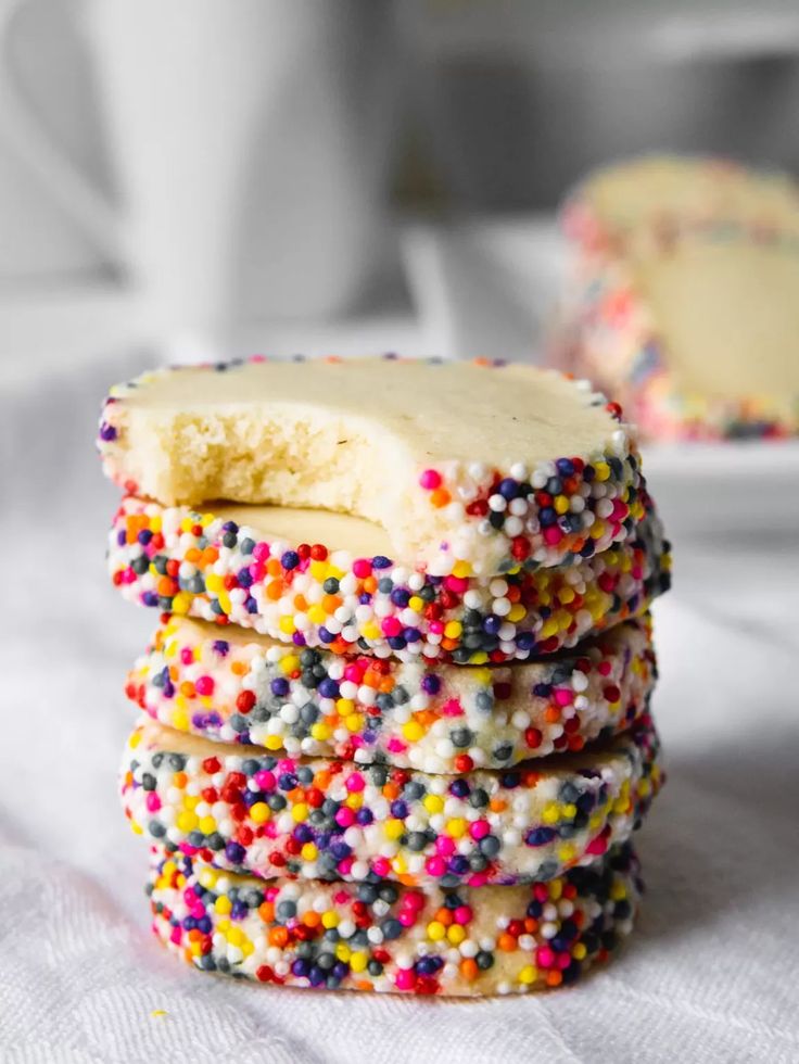 a stack of sprinkle covered cookies sitting on top of a white table cloth