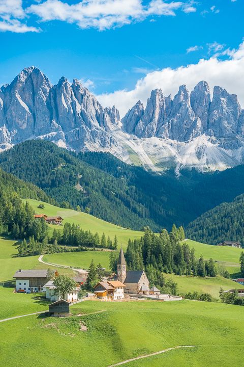 the mountains are covered in snow and green grass, with small houses on each side