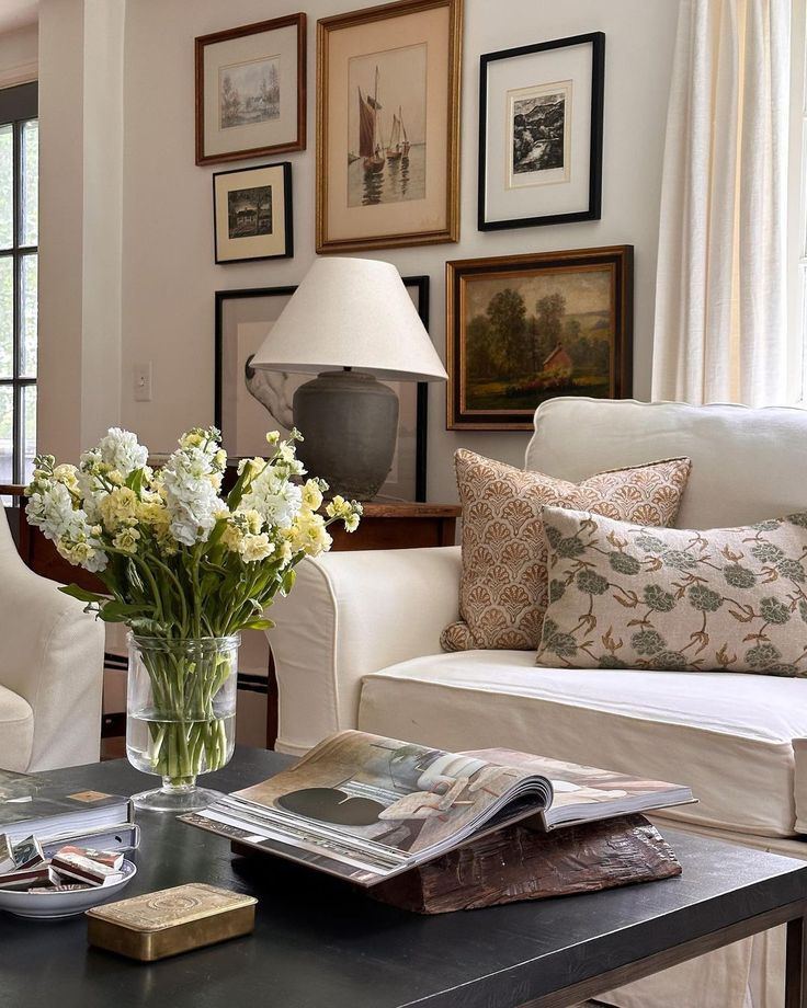 a living room filled with furniture and flowers in a vase on top of a coffee table