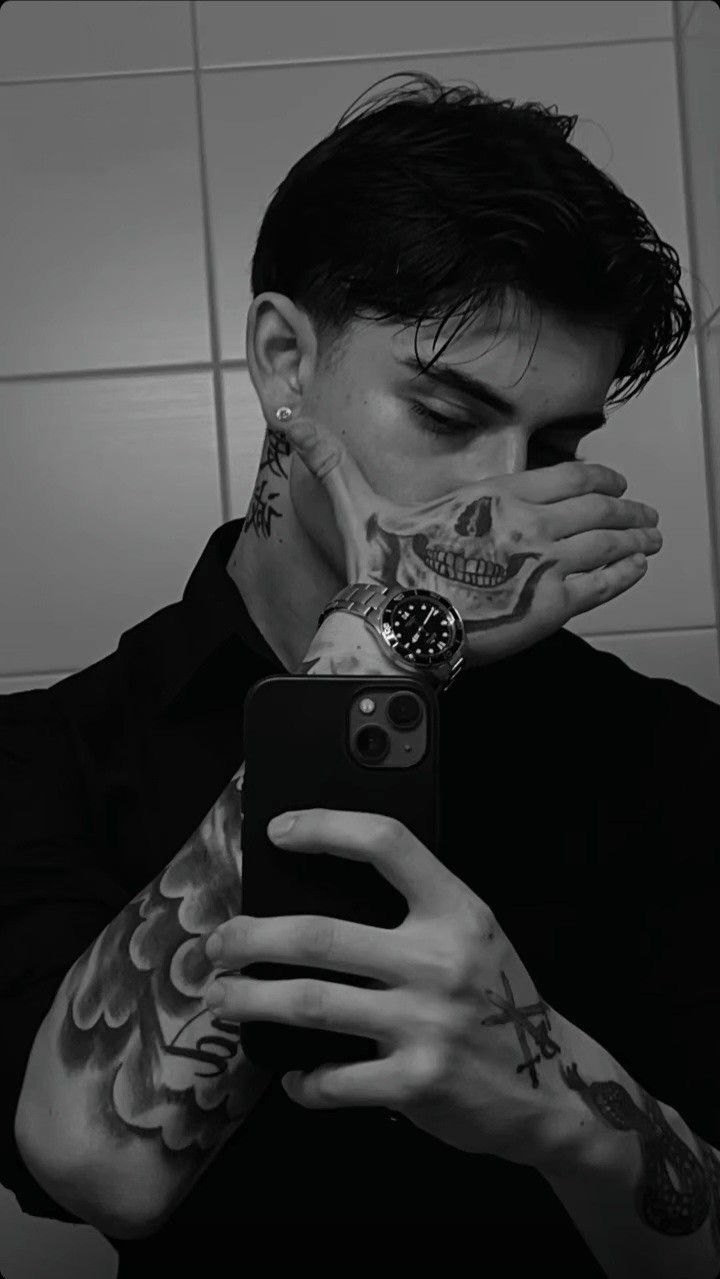 a man with tattoos taking a selfie in front of a mirror while holding his phone up to his face