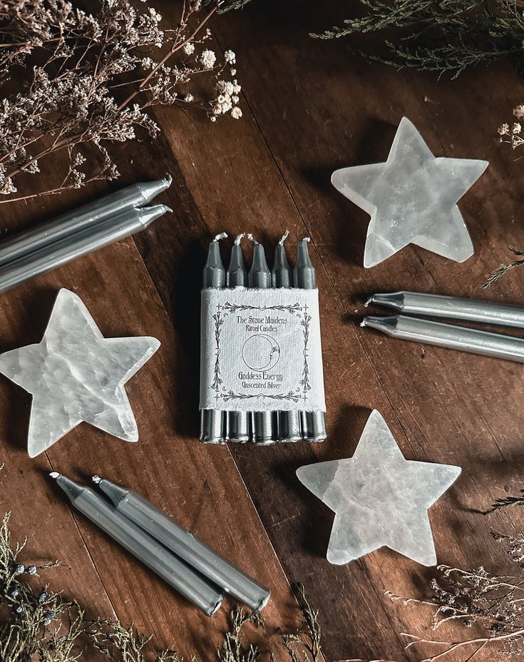 several metal stars are laying on a wooden table next to some pens and pencils