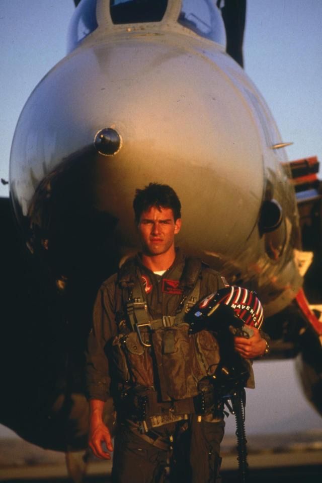 a man standing in front of an airplane with his hand on the engine and helmet