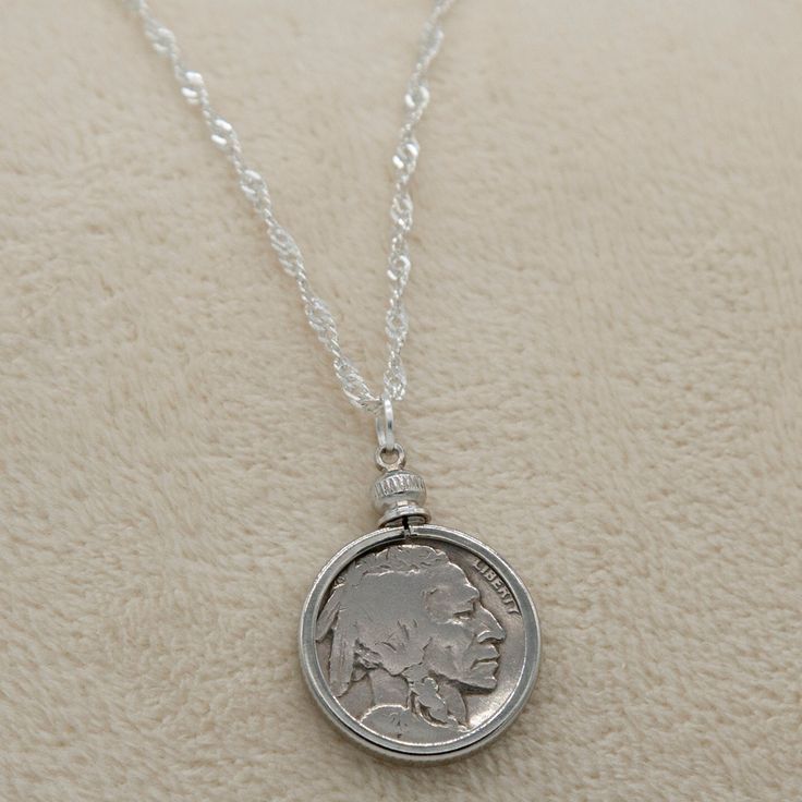 Introducing our exquisite Buffalo/Indian Head Nickel Necklace, a must-have accessory for history buffs, coin collectors, and vintage coin enthusiasts. This timeless piece effortlessly complements both casual and formal wear, making it a versatile addition to your jewelry collection. Featuring an authentic antique Buffalo Nickel from the early 1900s, each necklace tells a unique story of the past. Choose between our sophisticated 18-inch black cord or our elegant 20-inch silver plated braided rope chain, allowing you to customize the necklace to your personal style. Rest assured, every coin used in our necklaces is carefully cleaned before assembly, retaining the coin's original authenticity while enhancing its visual appeal. The bezel mount not only adds a touch of elegance but also serves Silver Necklaces With Coin Pendant For Vintage Collection, Vintage Medallion Coin Pendant Jewelry, Commemorative Coin Pendant Medallion Jewelry, Commemorative Medallion Coin Pendant Jewelry, Antique Medallion Jewelry With Coin Pendant, Vintage Antique Silver Jewelry With Coin Pendant, Nickel Free Medallion Jewelry For Commemoration, Vintage Jewelry With Coin Pendant For Collectors, Heirloom Silver Necklace With Coin Pendant