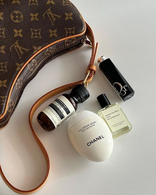 the contents of a handbag are laid out next to an empty bottle and purse